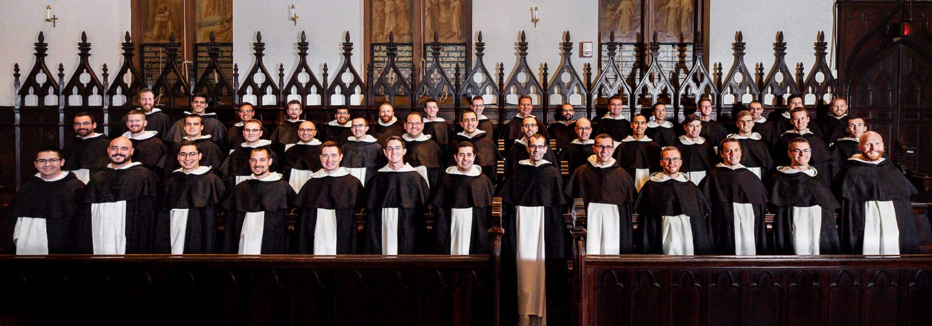 A large group of men in choir robes, standing together in a church setting.